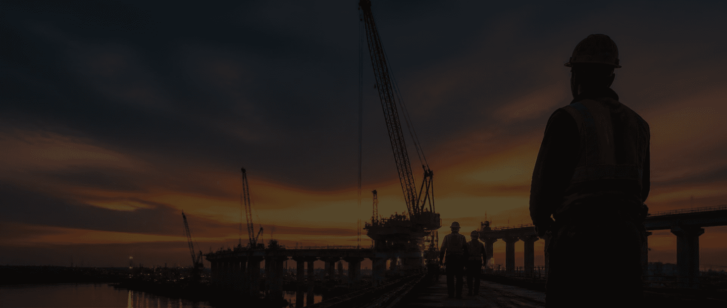 Construction workers and cranes on a bridge project at sunset